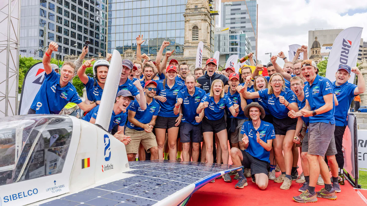 Belgian student solar racing team celebrating World Solar Challenge success with a solar car.